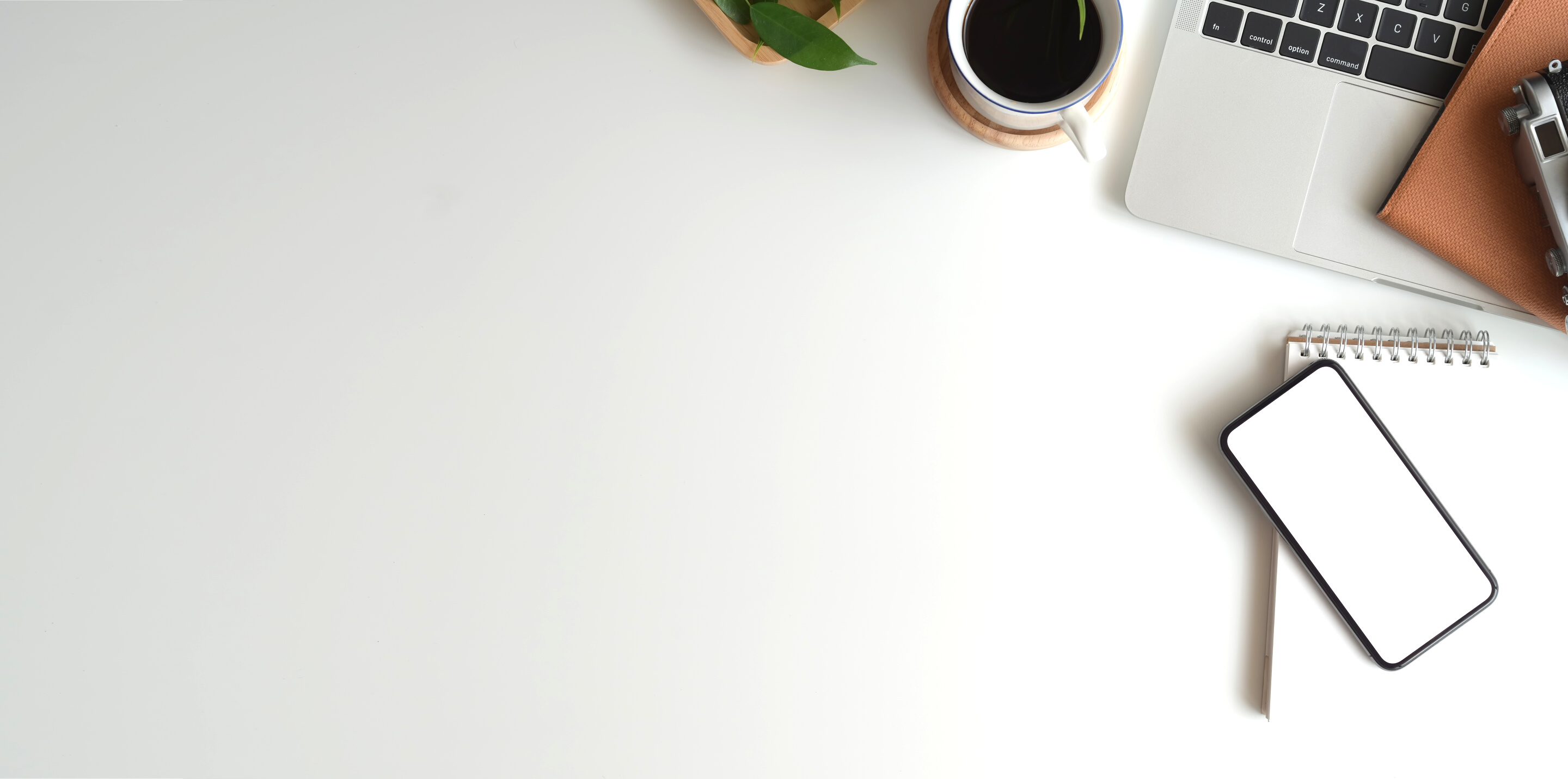 White Ceramic Cup Beside a Laptop on White Table